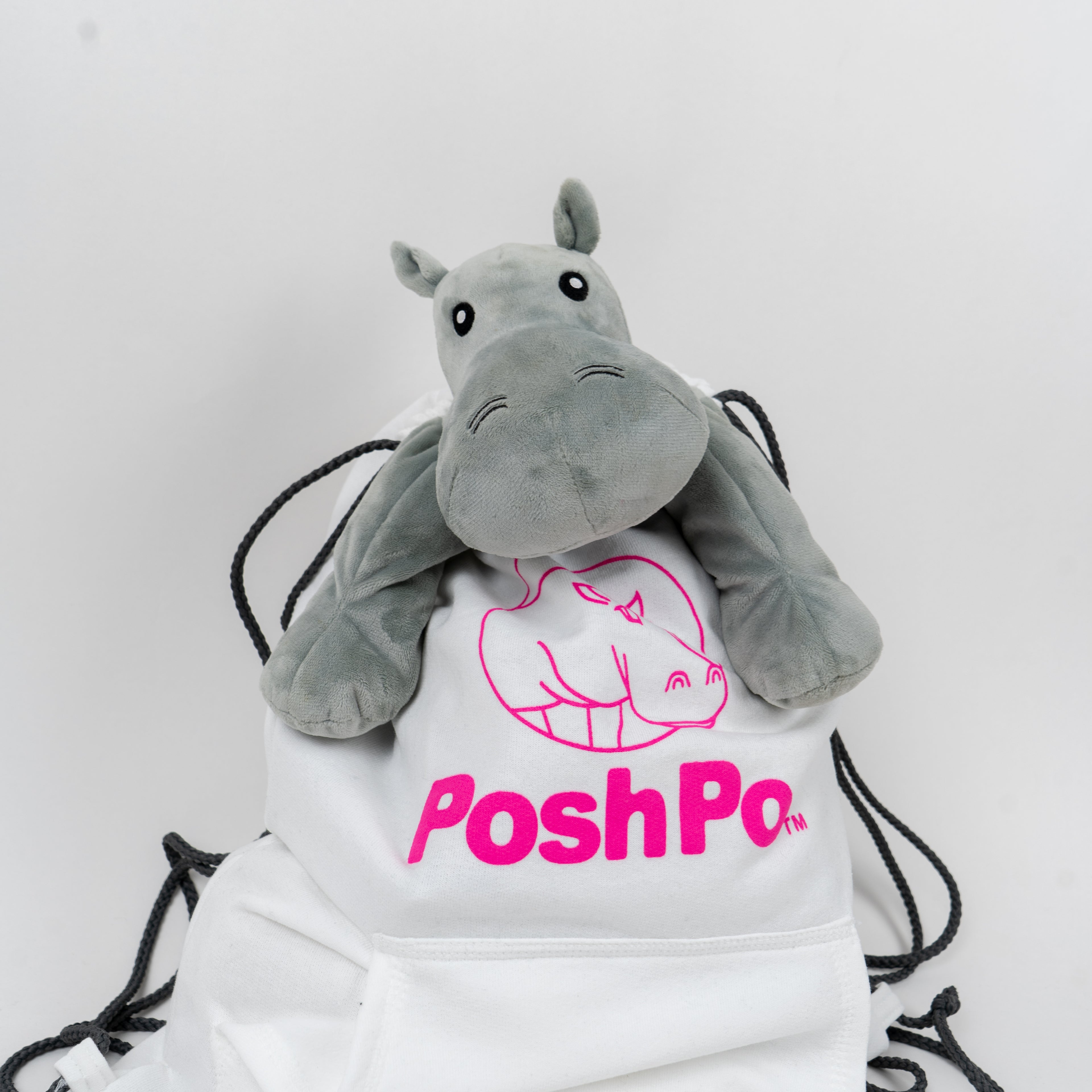 White bag with pink 'PoshPo' logo and plush hippo toy on a white background