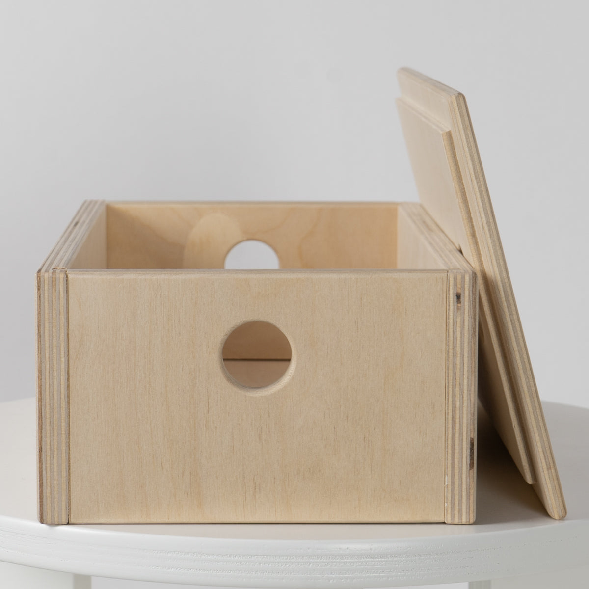 Wooden box with a circular hole on a white surface