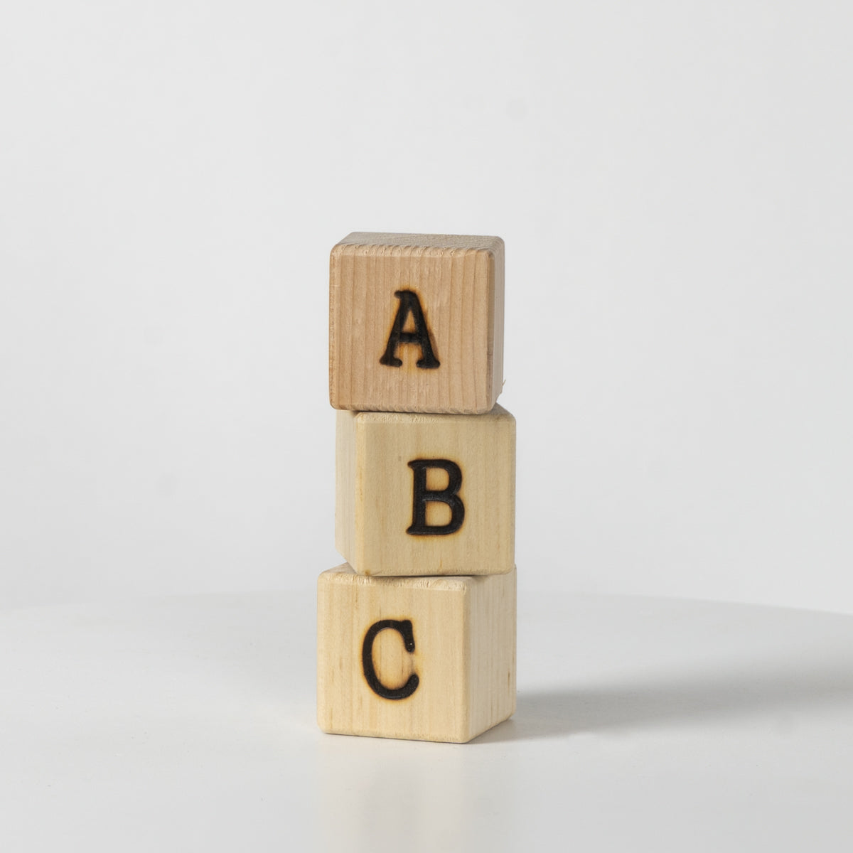 Three wooden blocks with letters A, B, and C on a light gray background