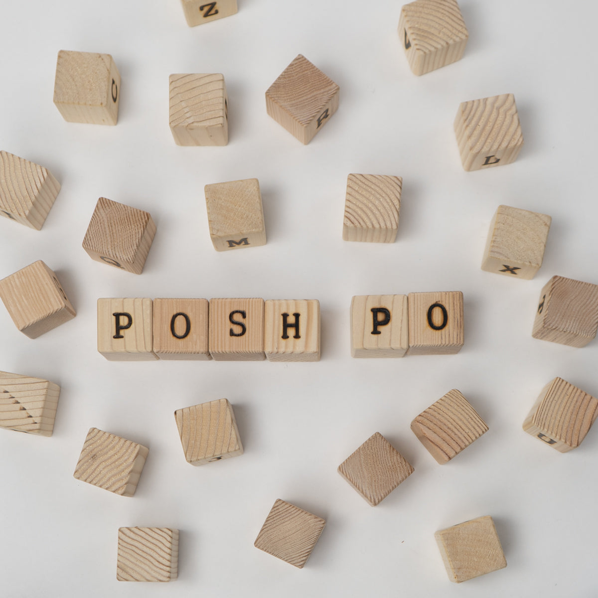 Wooden blocks with letters spelling 'POSH' on a light background