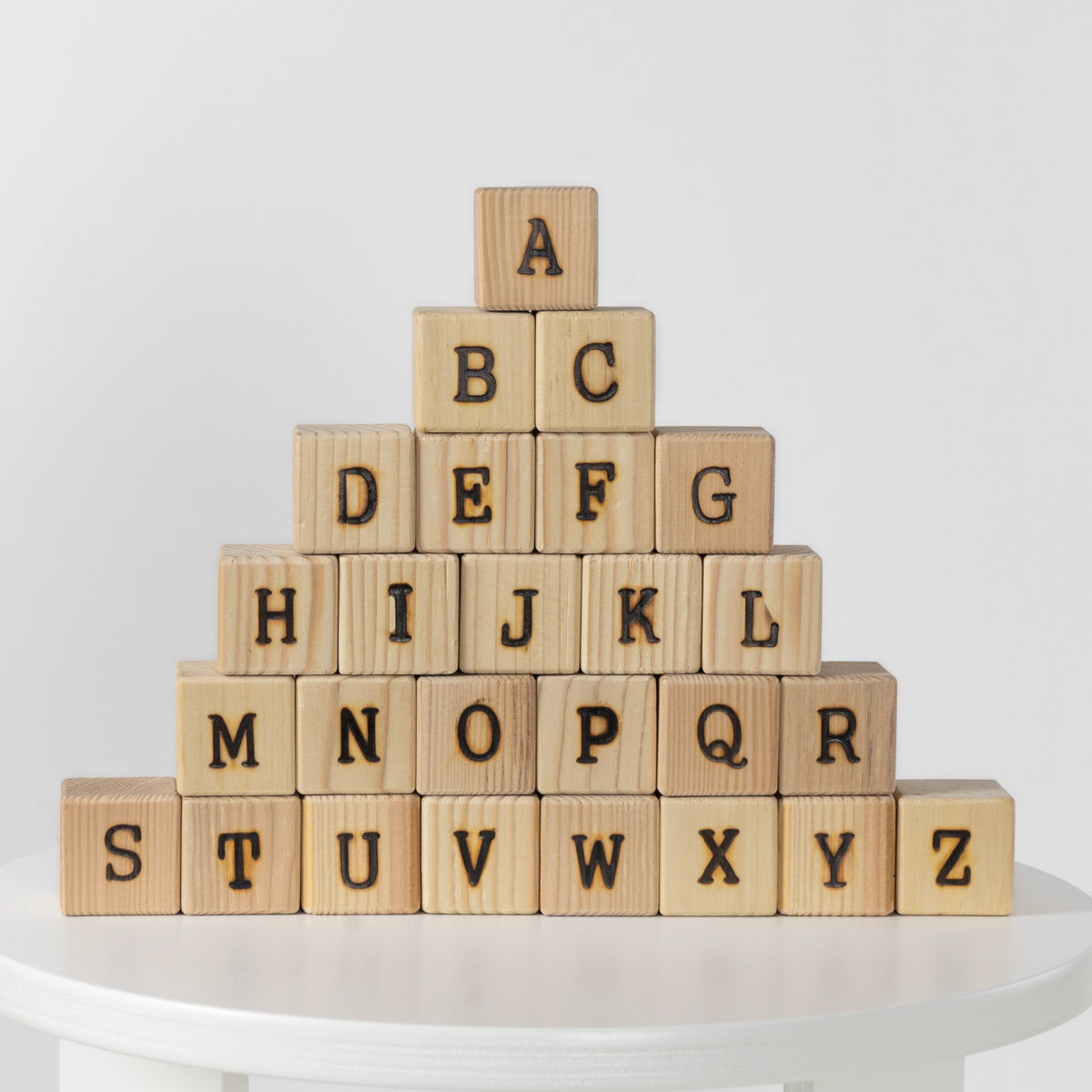 Wooden blocks with letters forming a pyramid on a white surface