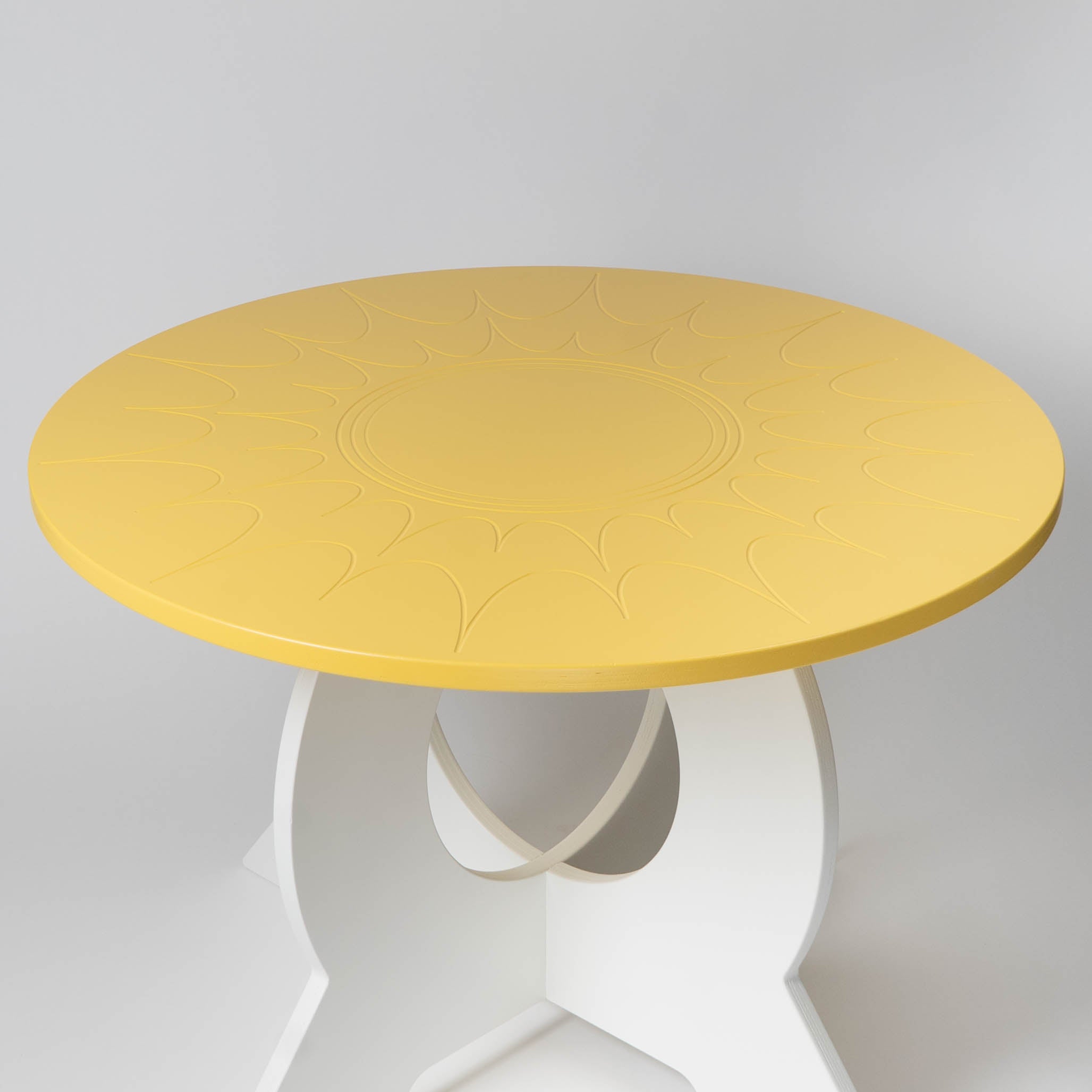 Round yellow table with white base on a light gray background