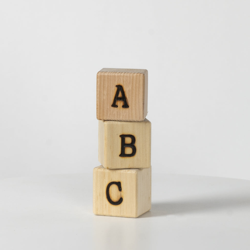 Three wooden blocks with letters A, B, and C on a light gray background