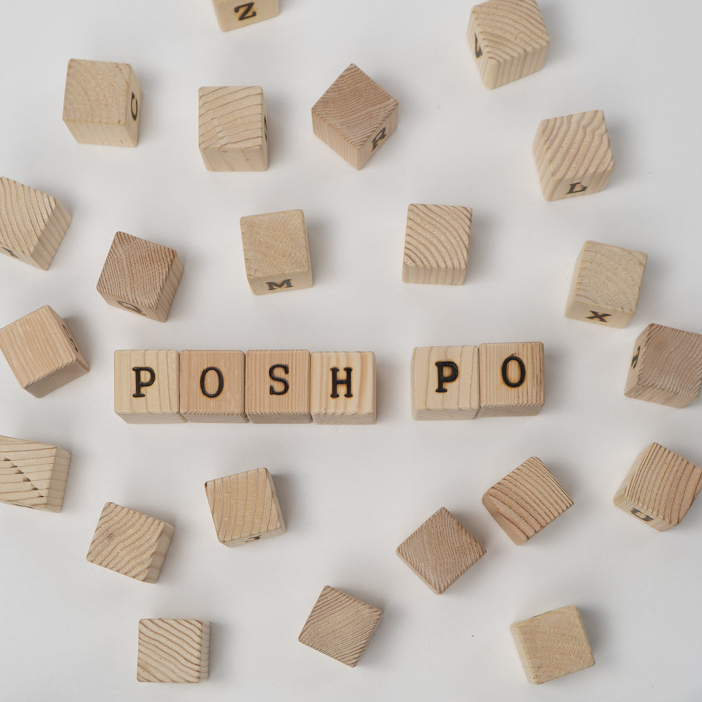 Wooden blocks with letters spelling 'POSH' on a light background