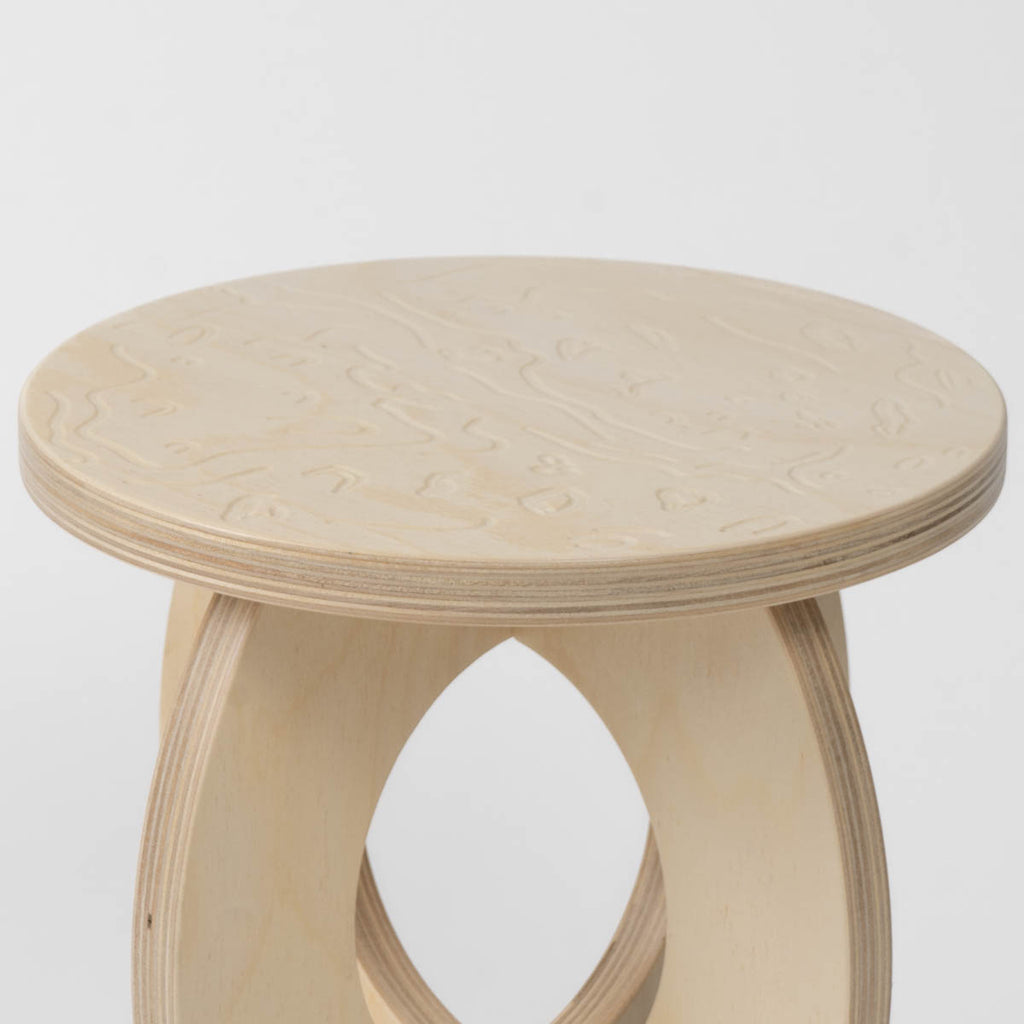 Wooden stool with a round top and etched Mars design on top on a white background
