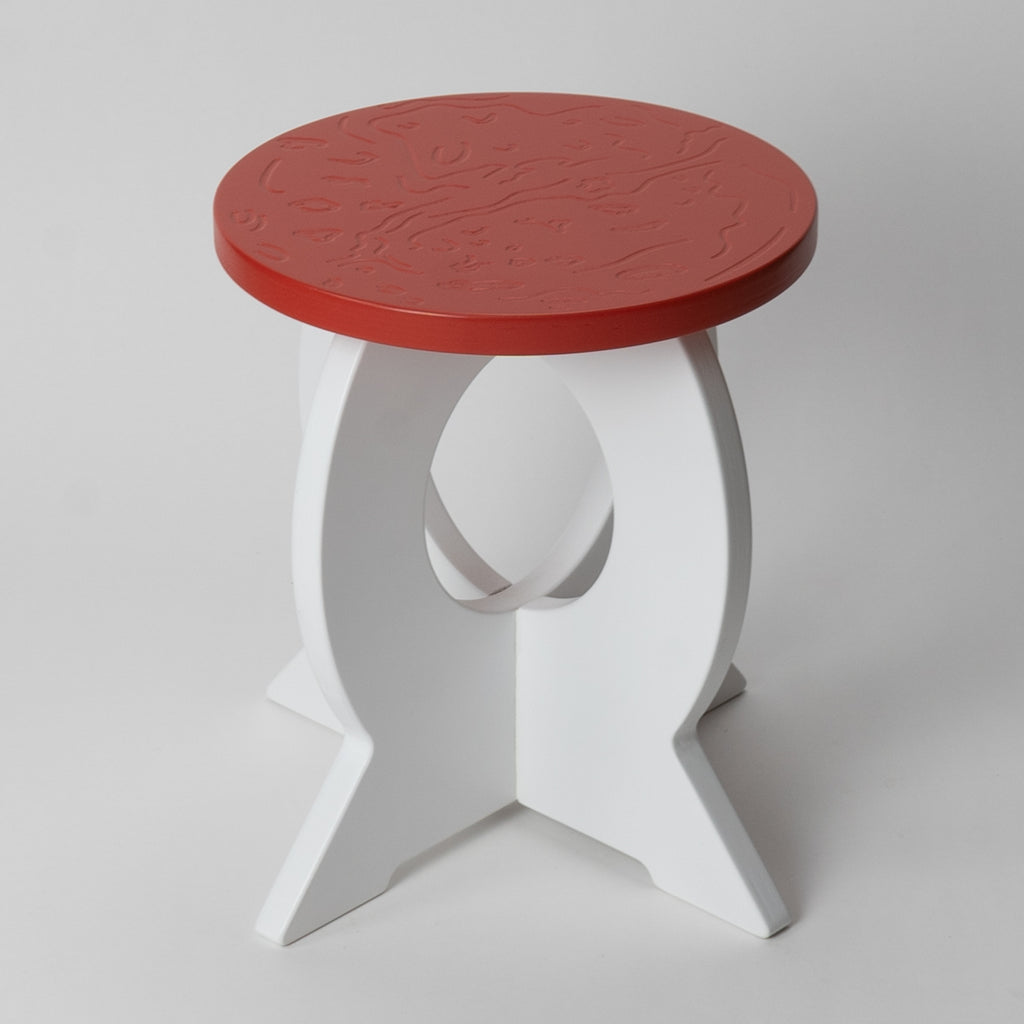 Small round wooden stool with a red top and white base on a light gray background